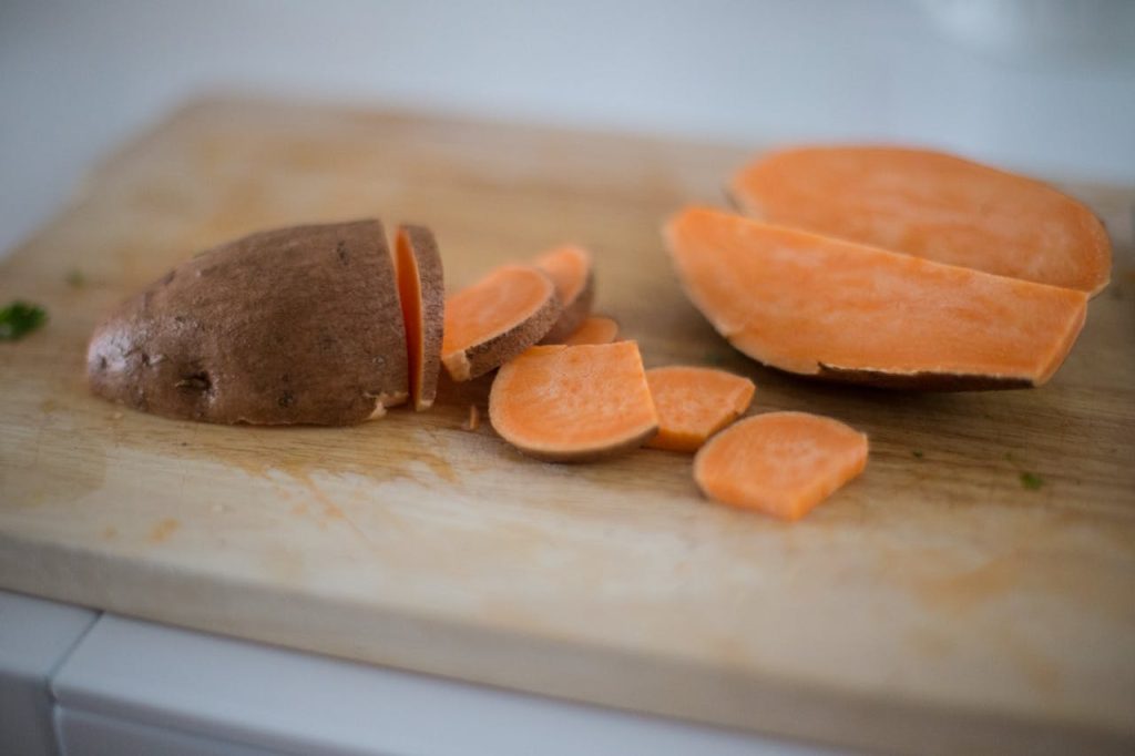 Close-up of sliced sweet potato on a wooden cutting board, perfect for cooking inspiration.